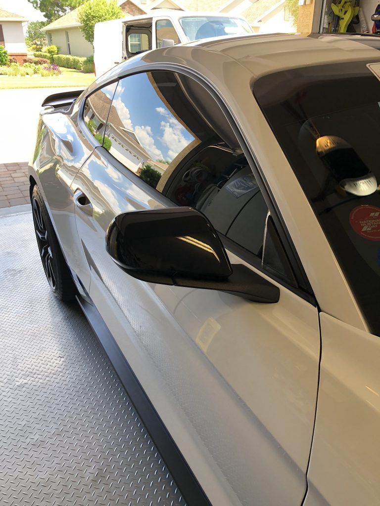 A white mustang is parked in a garage.