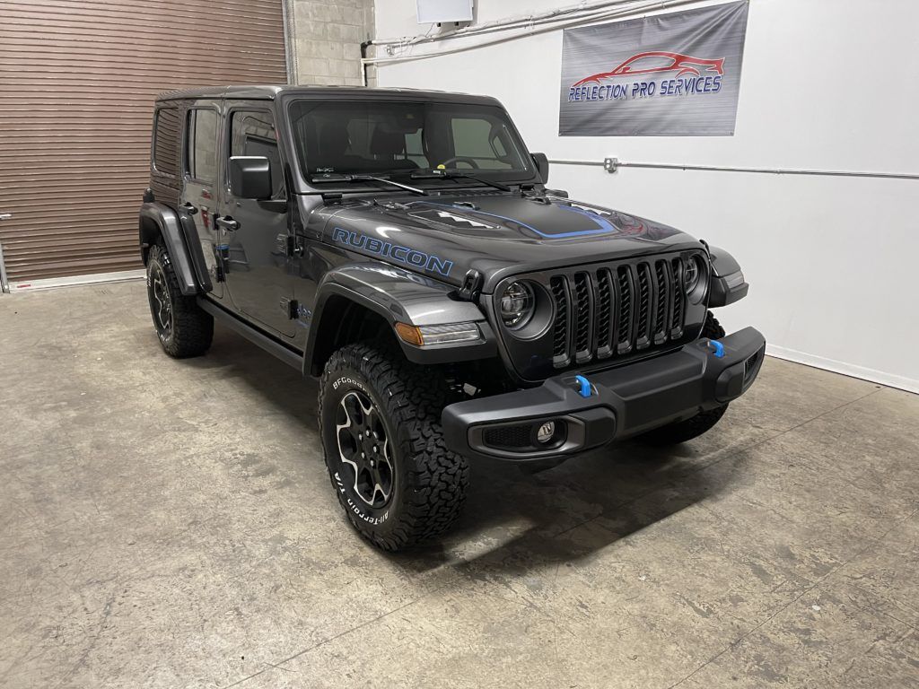 A jeep wrangler is parked in a garage next to a wall.