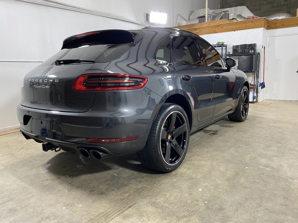 A black porsche macan is parked in a garage.