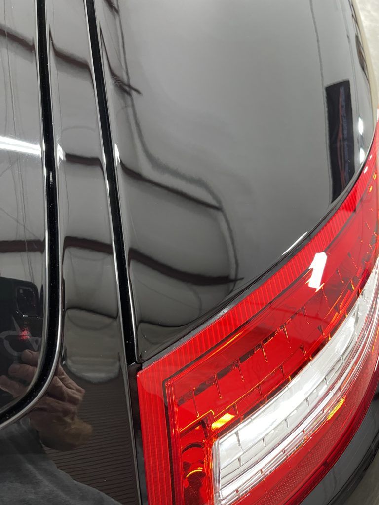 A close up of a black car with a red tail light.