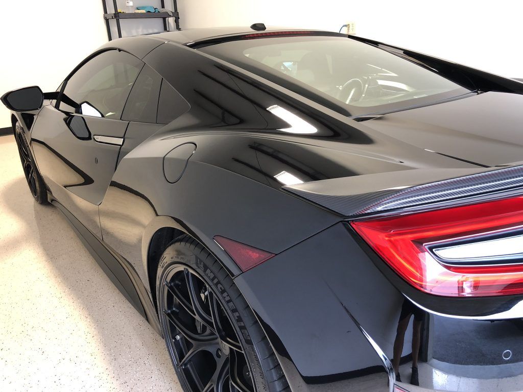 A black sports car is parked in a garage.