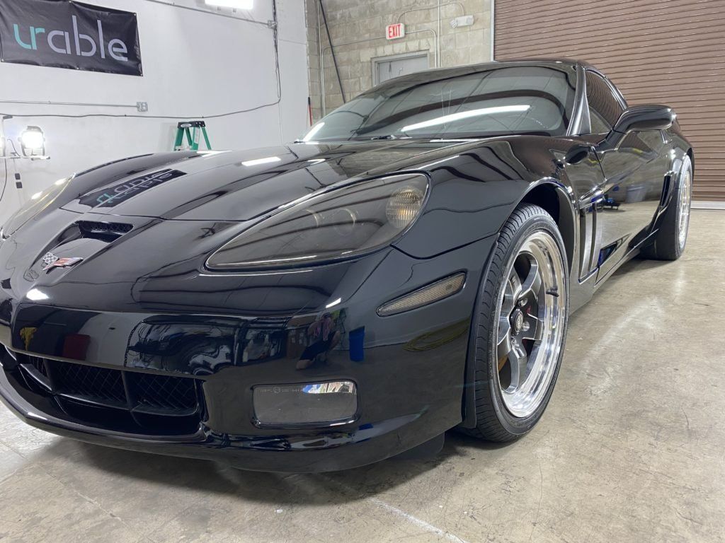 A black sports car is parked in a garage.