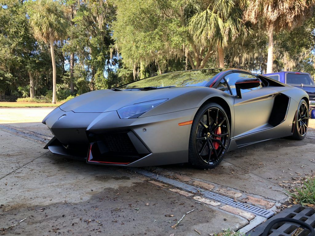 A gray lamborghini aventador is parked on the side of the road.