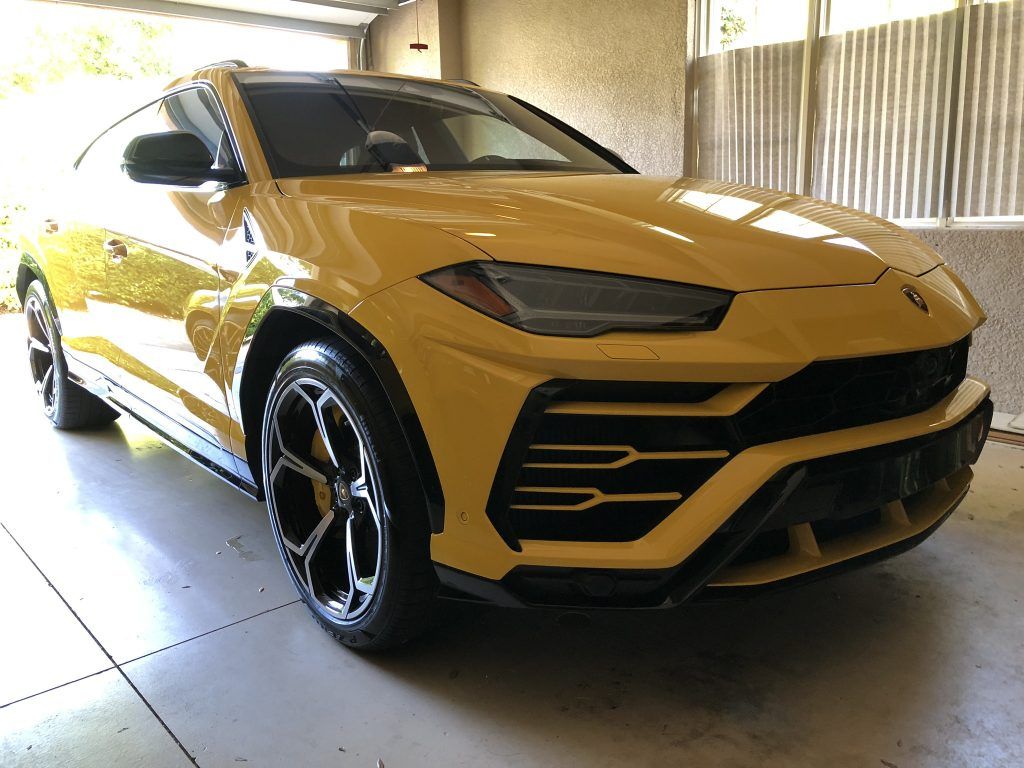 A yellow lamborghini urus is parked in a garage.