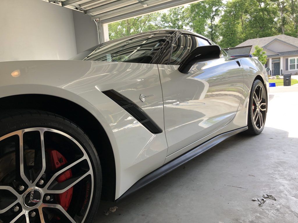 A white sports car is parked in a garage.