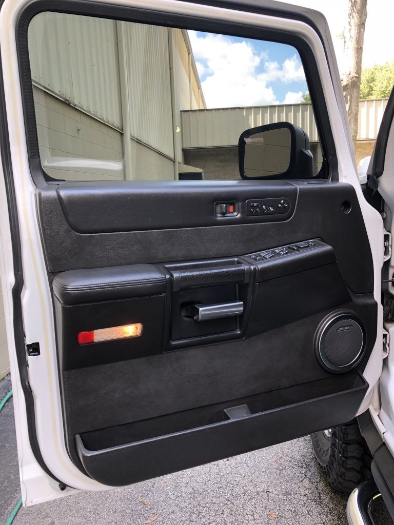The door of a white hummer h2 is open.