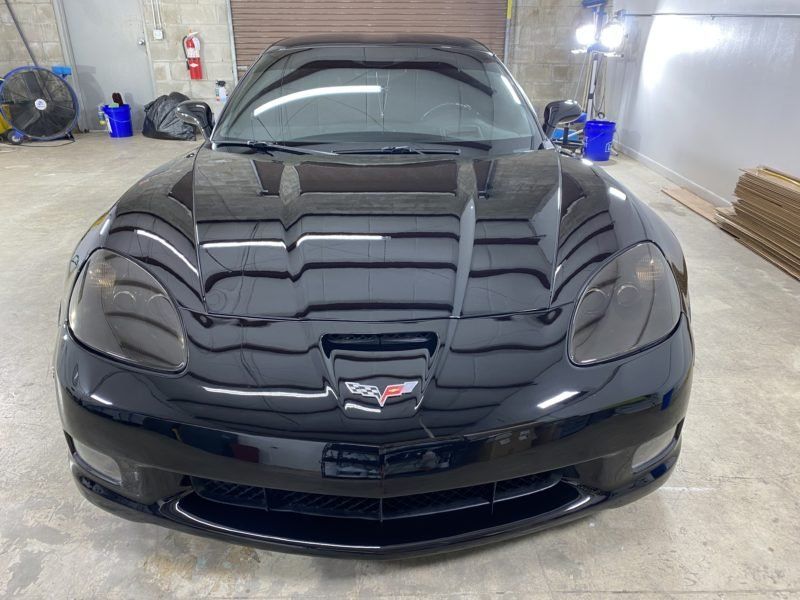 A black sports car is parked in a garage.