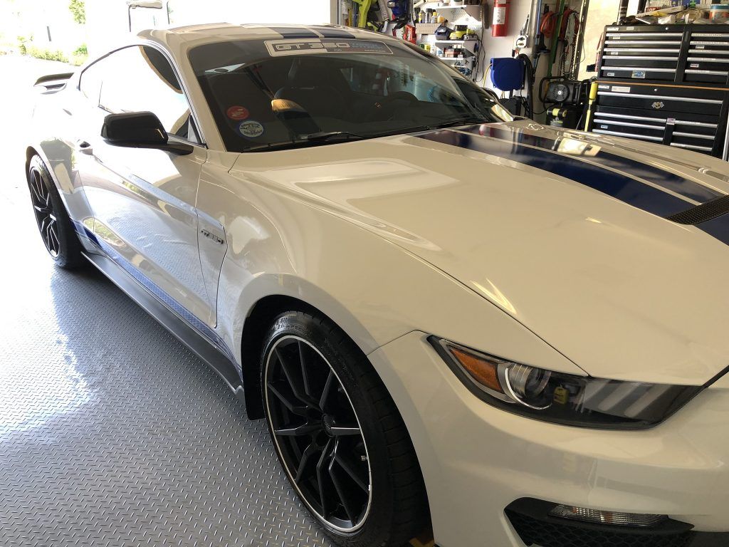 A white ford mustang is parked in a garage.