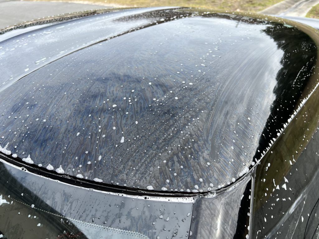 The roof of a black car is covered in soap bubbles