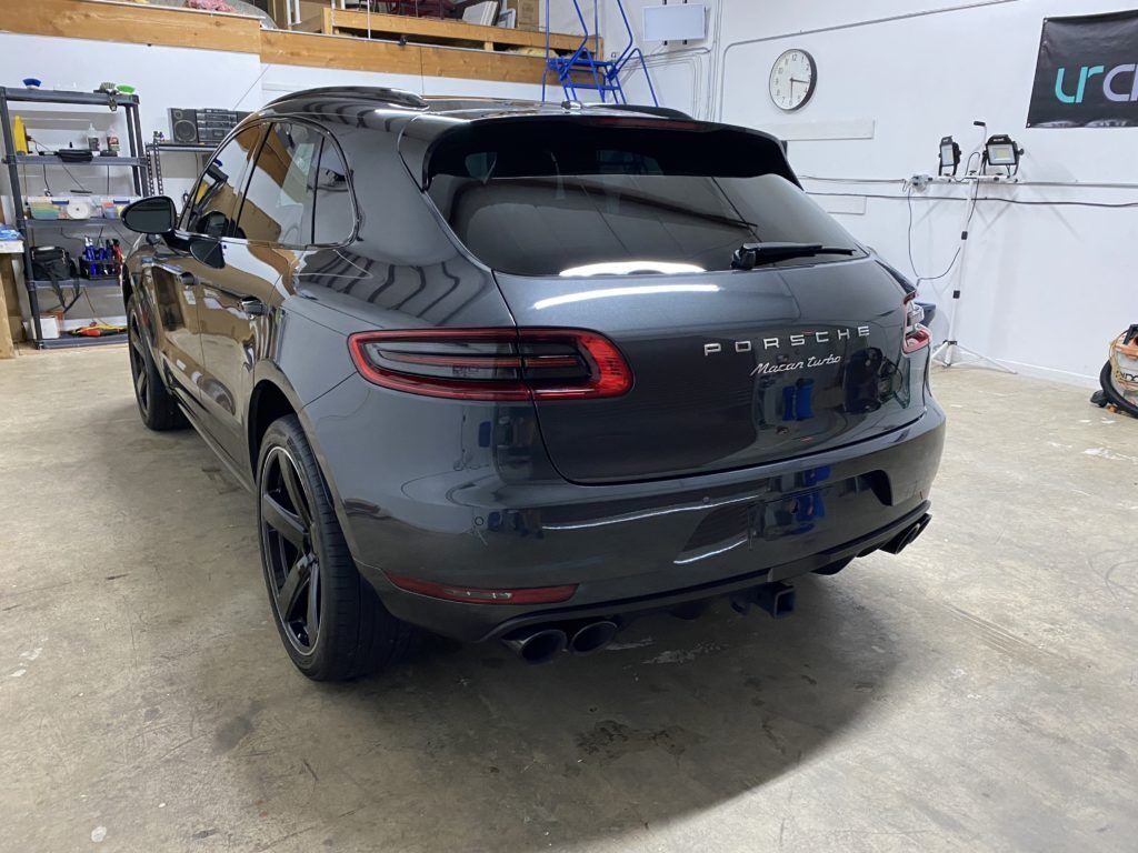 A black porsche macan is parked in a garage.