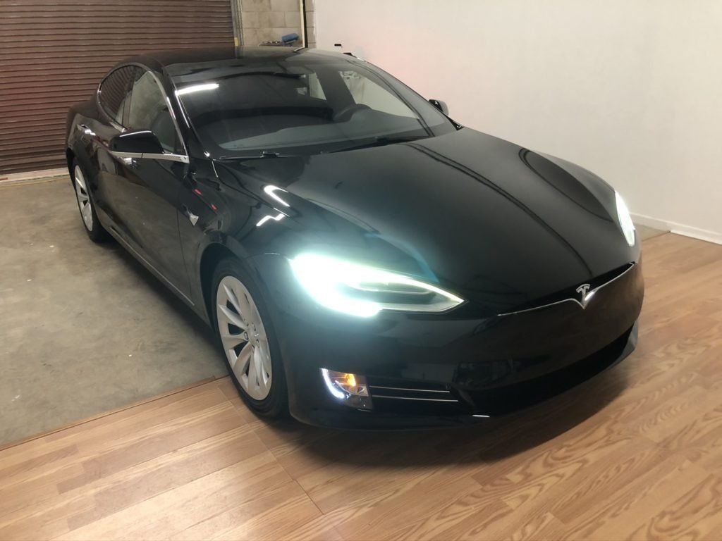 A black tesla model s is parked in a garage.