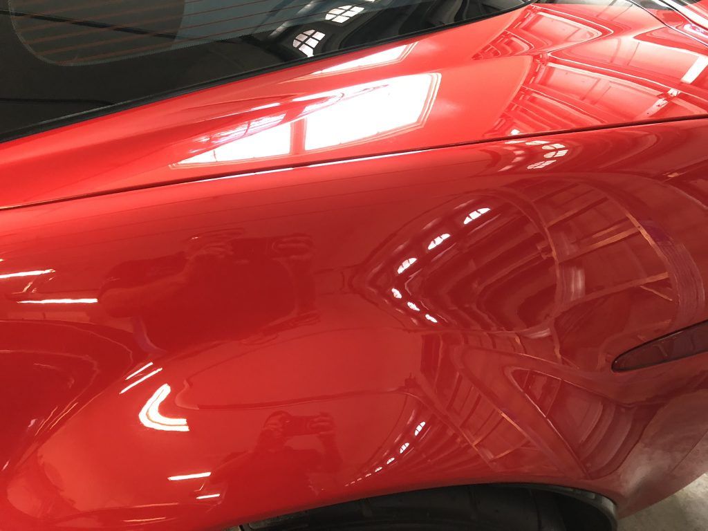 A close up of a red car 's fender and windshield