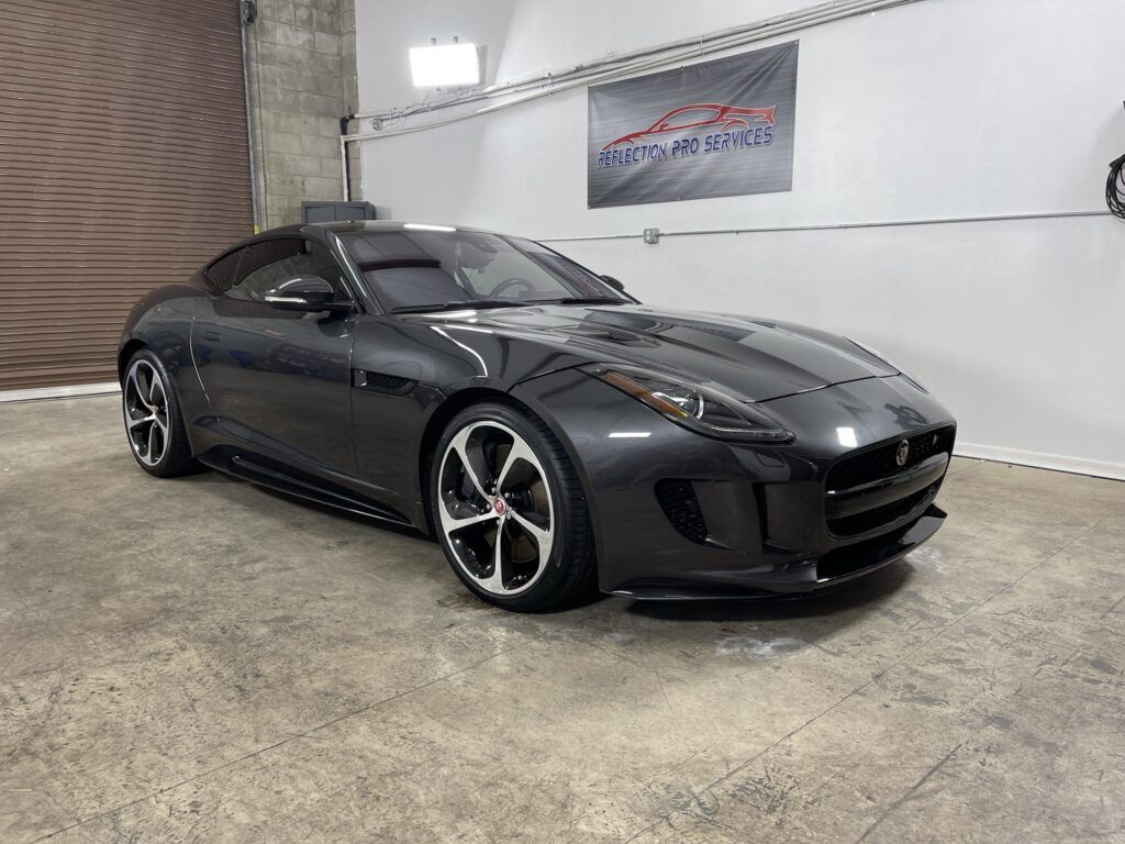 A black jaguar f type is parked in a garage.