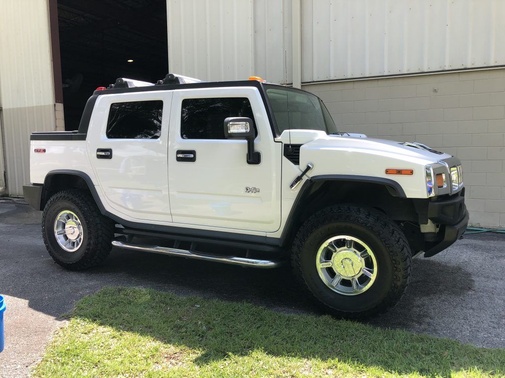 A white hummer h2 is parked in front of a building.