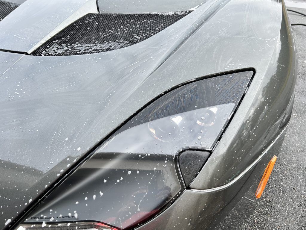 A close up of a car 's headlight and hood