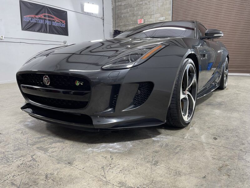 A black jaguar f type is parked in a garage.