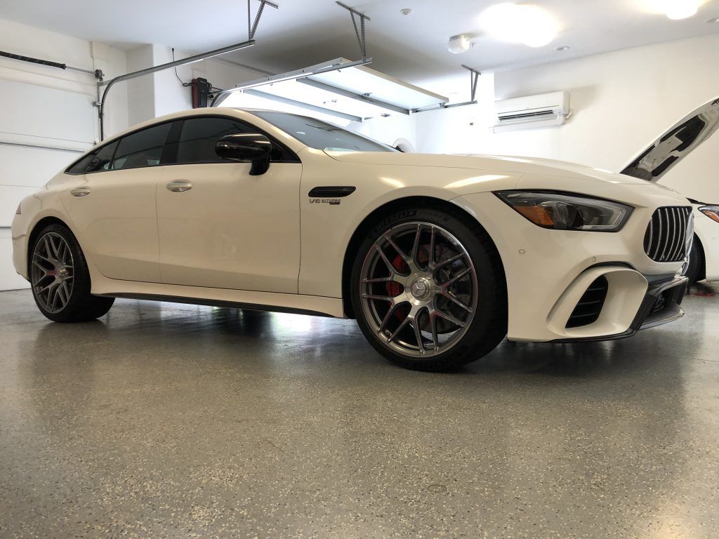 A white mercedes amg gt 63 s is parked in a garage.