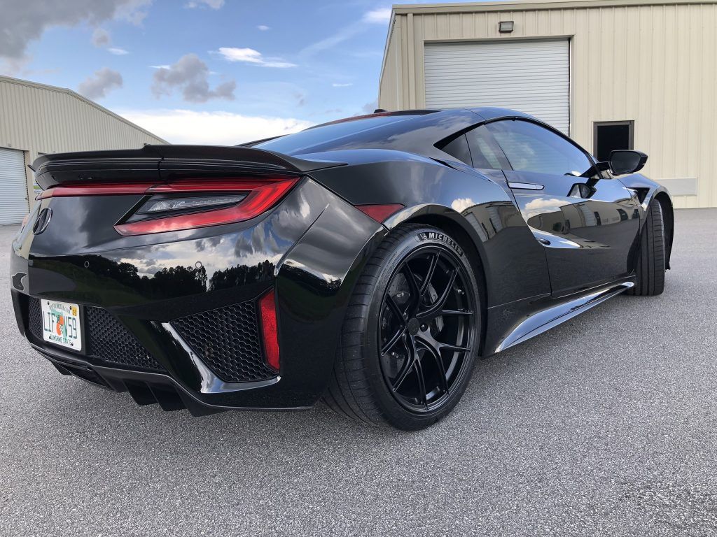 A black sports car is parked in front of a garage.