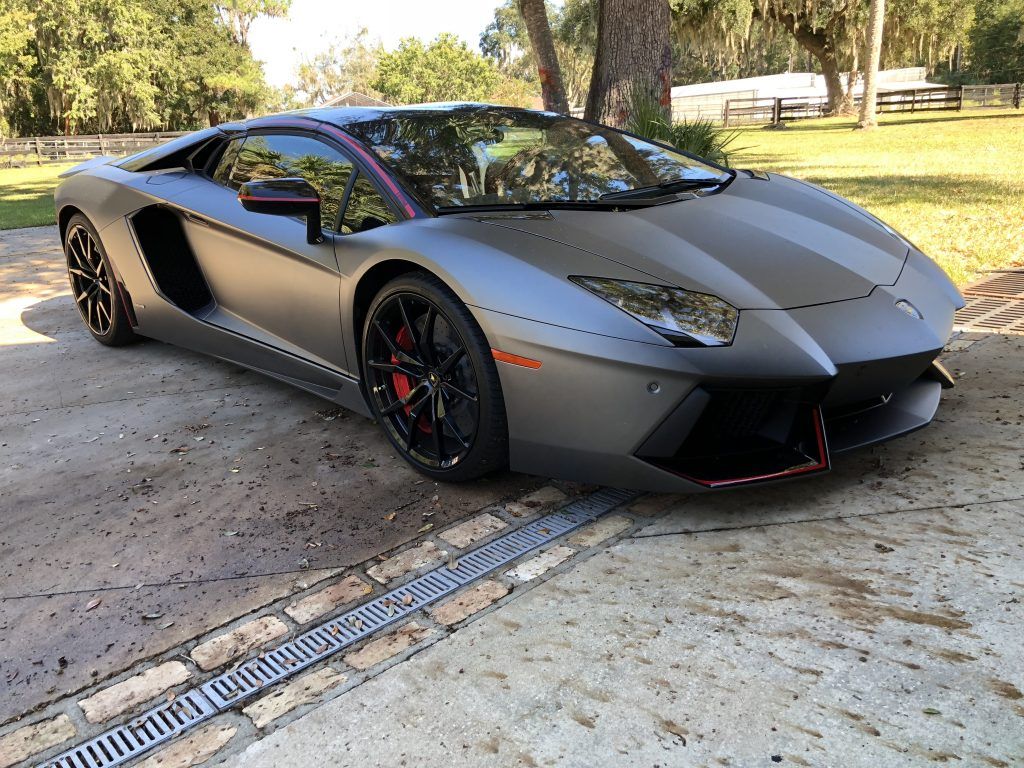 A black lamborghini aventador is parked in a driveway.