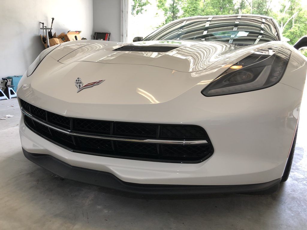 A white sports car is parked in a garage.