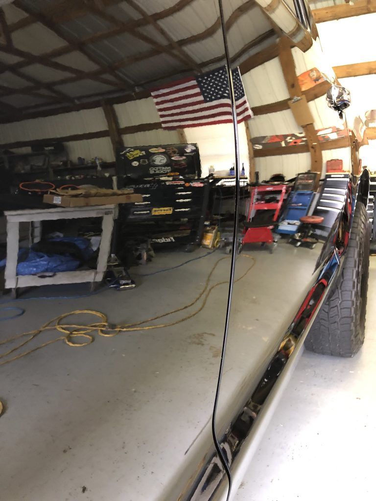 A car is parked in a garage with an american flag hanging from the ceiling.