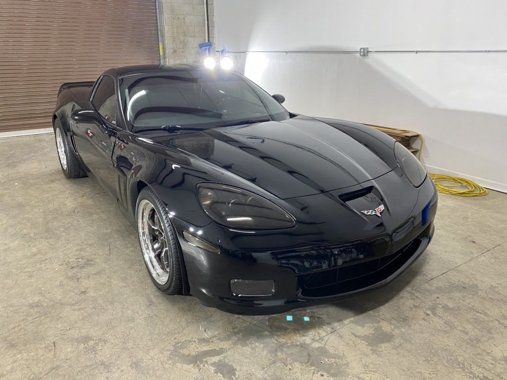 A black corvette is parked in a garage.