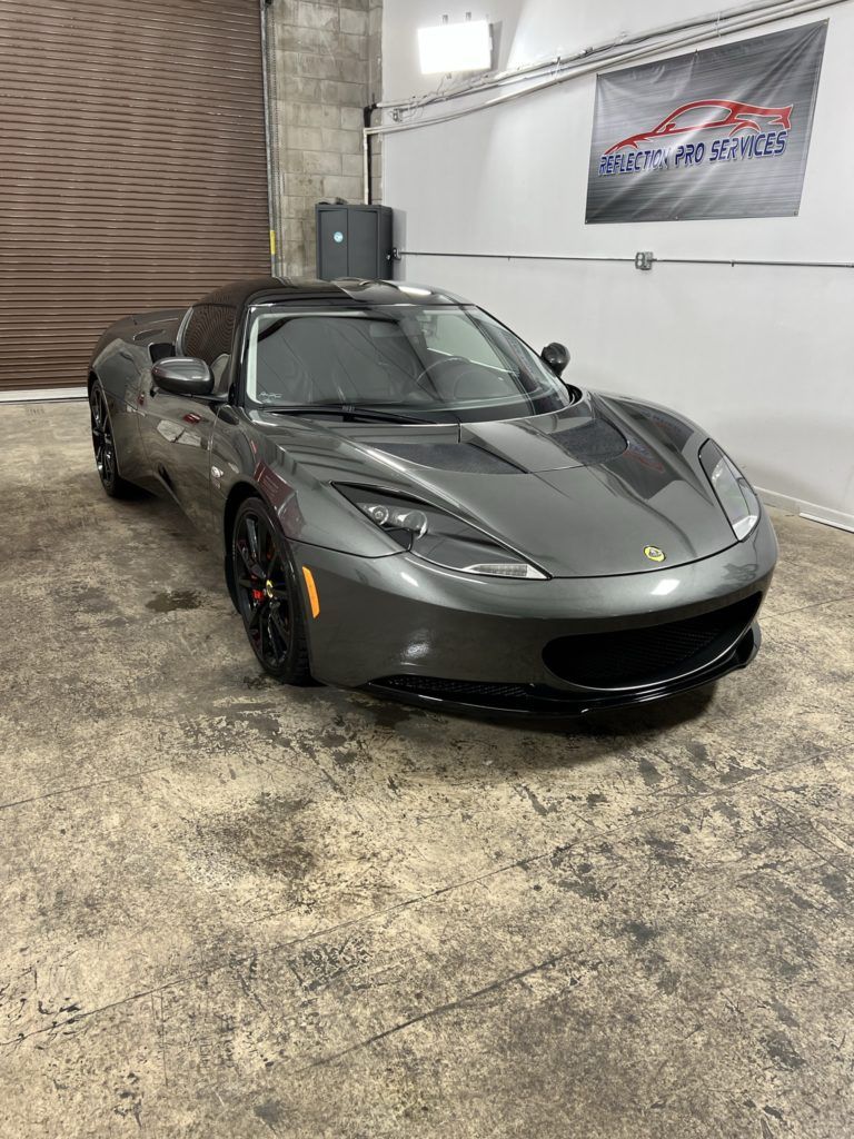 A gray sports car is parked in a garage.