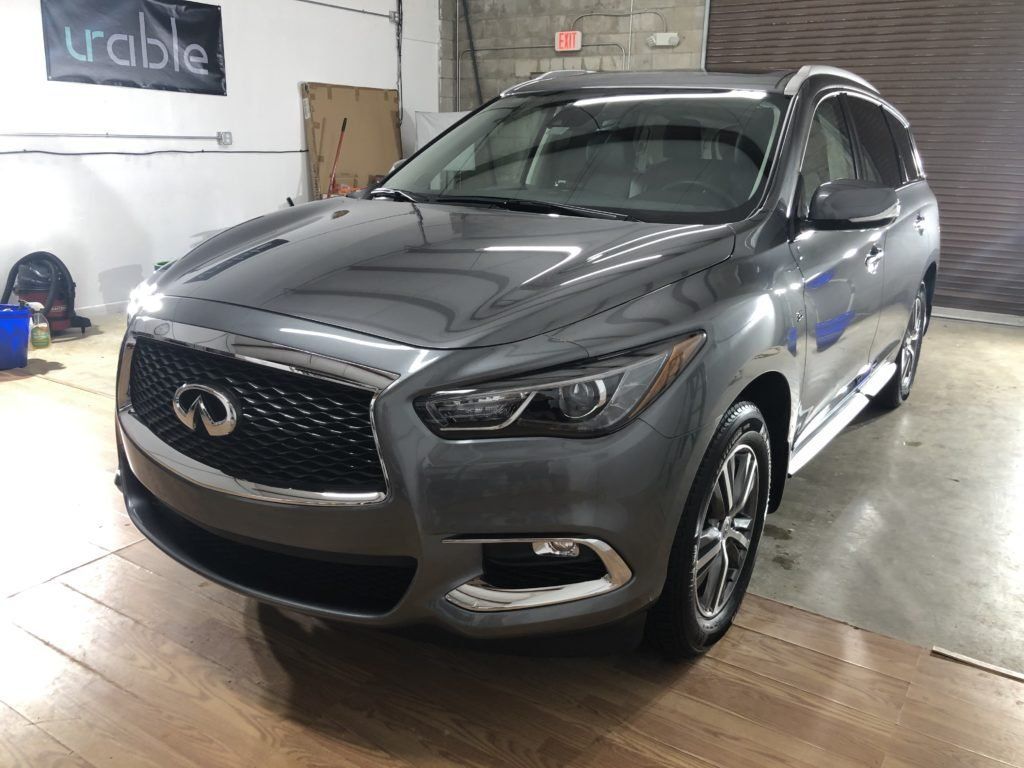 A gray infiniti qx60 is parked in a garage.
