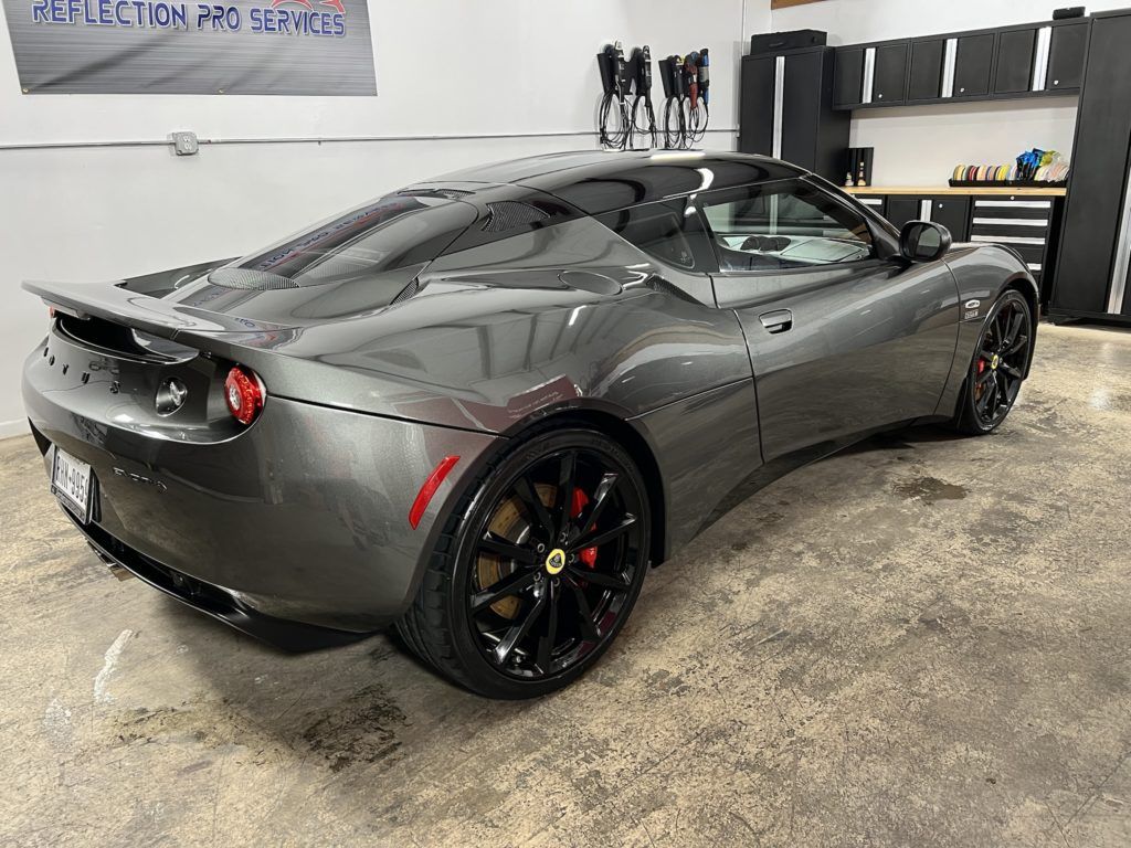 A gray sports car is parked in a garage.