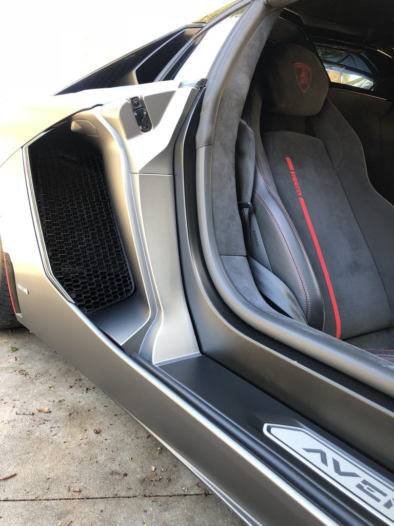 A black lamborghini aventador is parked on the side of the road.