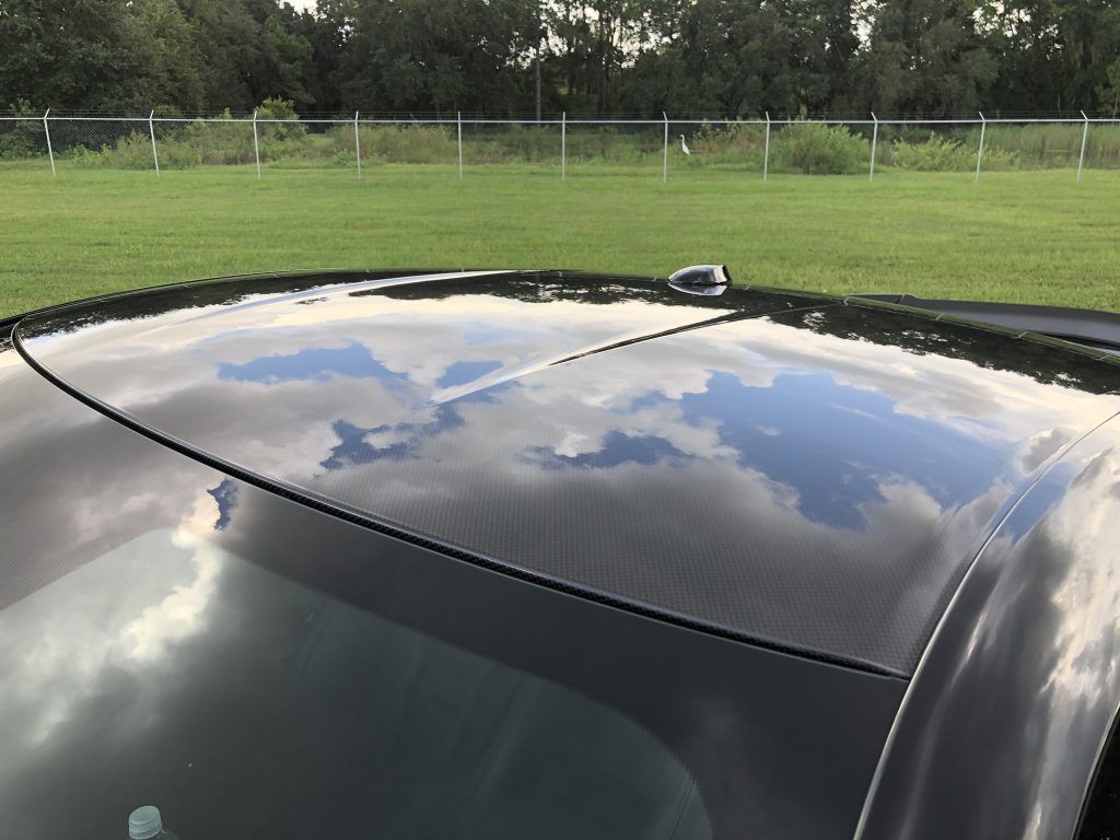 The roof of a black car is reflected in the windshield