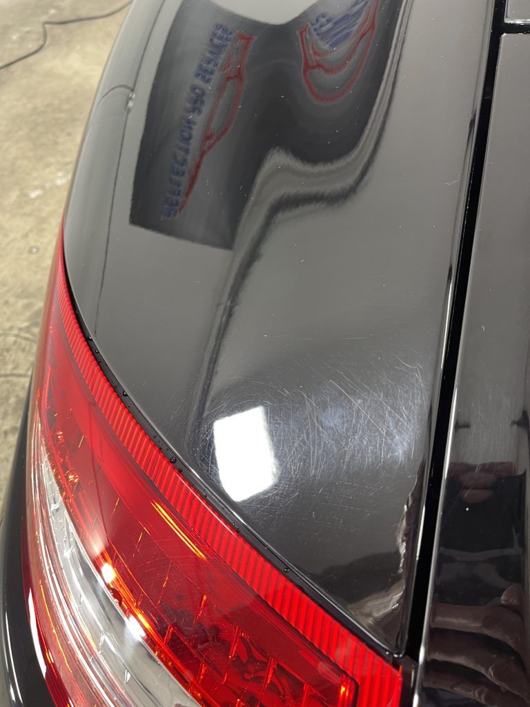A close up of a black car with a red tail light