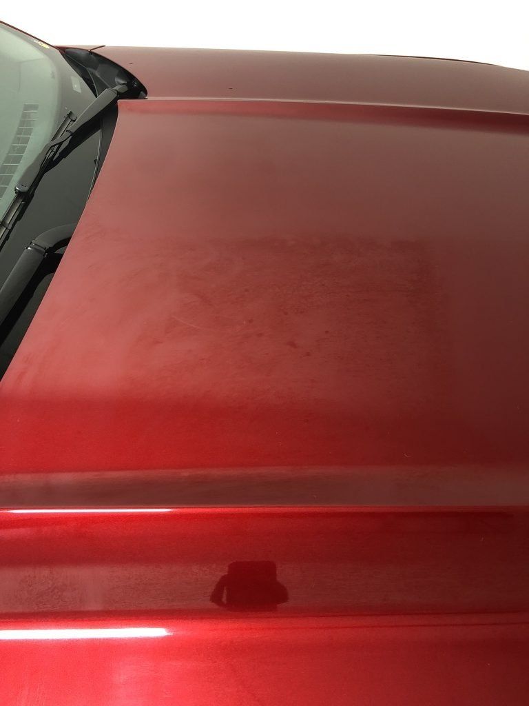 A close up of a red car hood and windshield