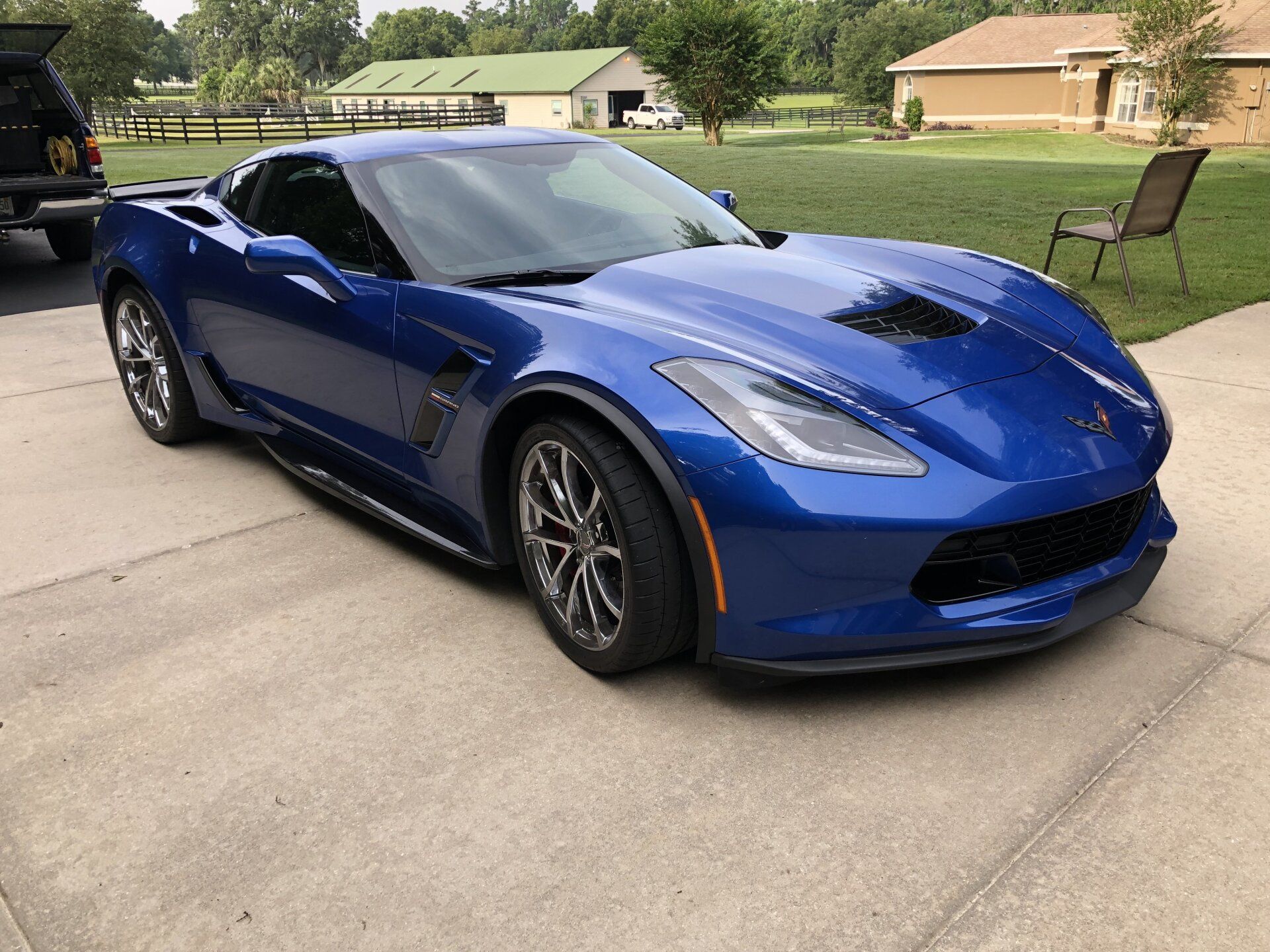 A blue sports car is parked in a driveway next to a house.