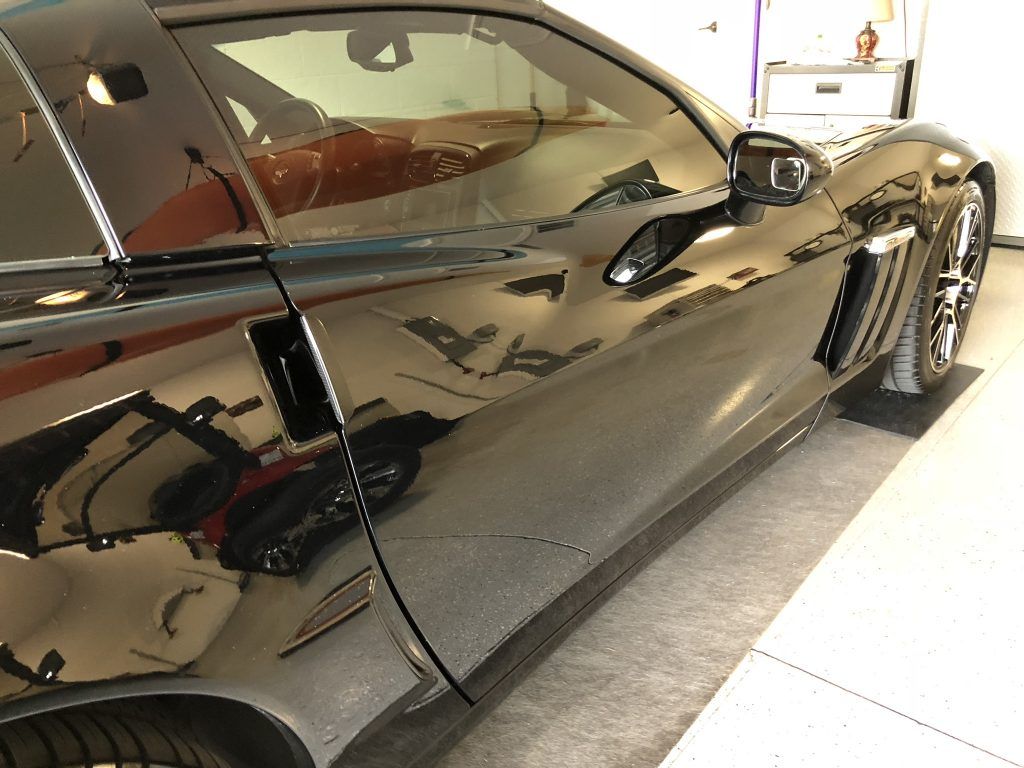 A black sports car is parked in a garage