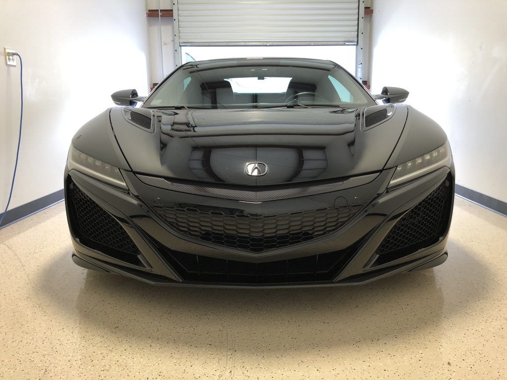 A black sports car is parked in a garage.