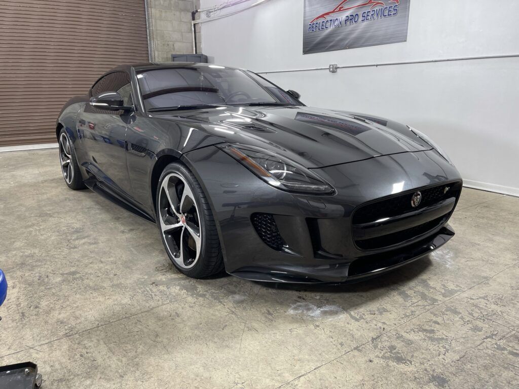 A black jaguar f type is parked in a garage.
