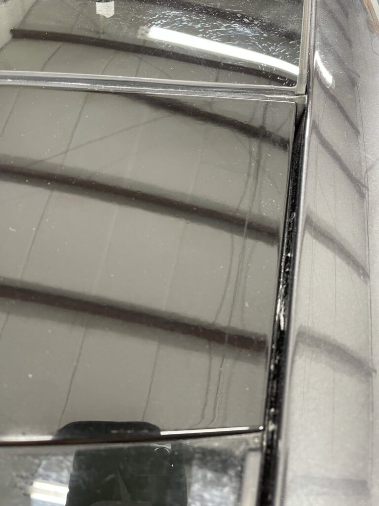 A close up of a black car hood with a reflection of a building in it.