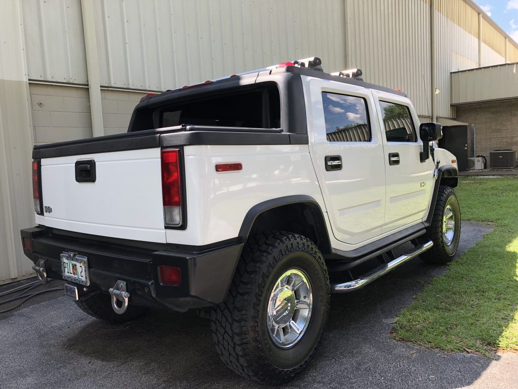 A white hummer truck is parked in front of a building.
