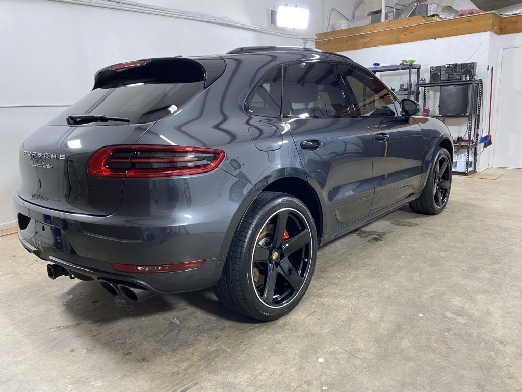 A gray porsche macan is parked in a garage.