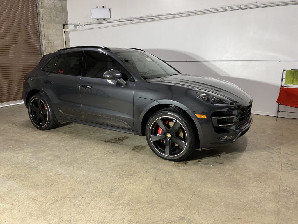 A gray porsche macan turbo is parked in a garage.
