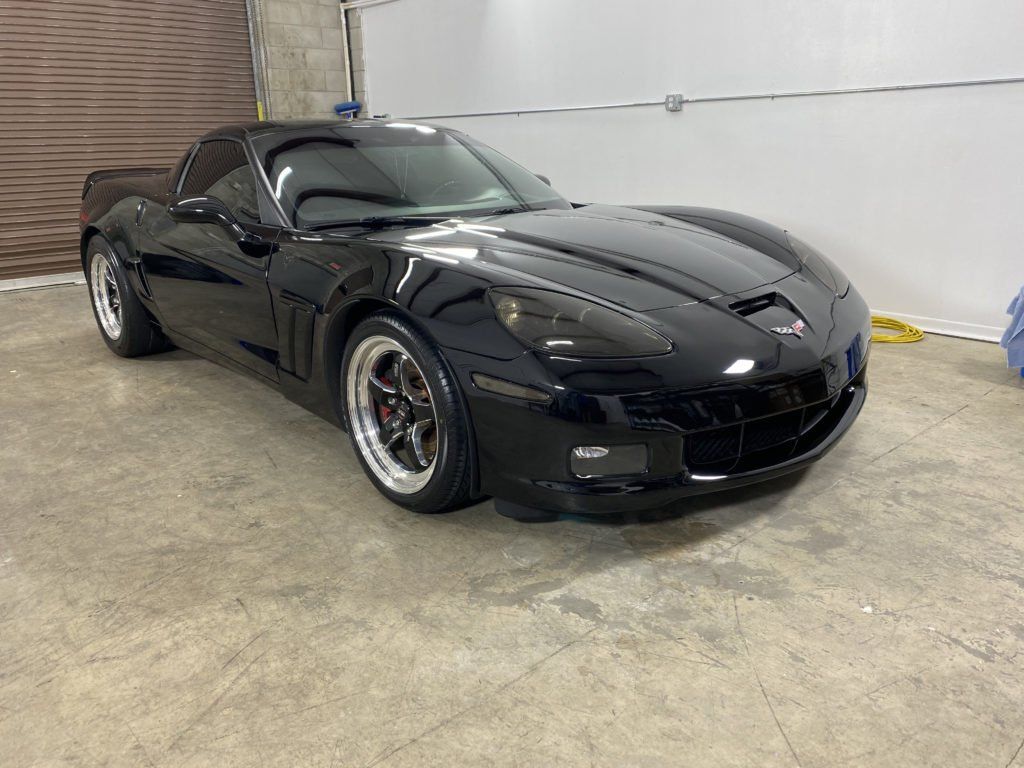 A black corvette is parked in a garage.