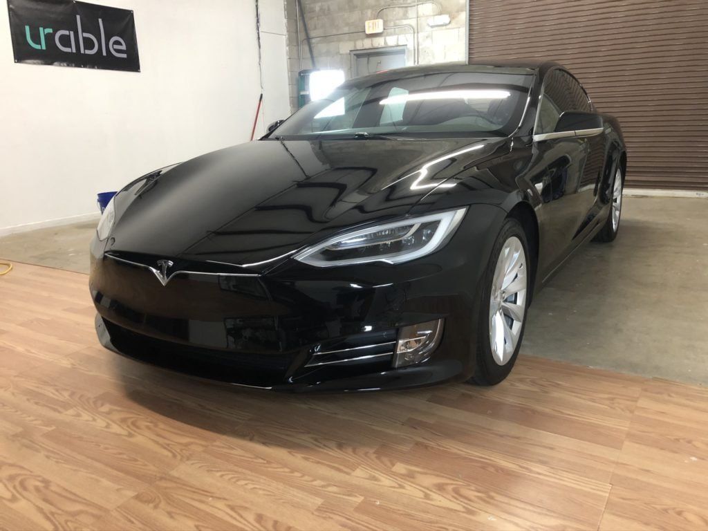 A black tesla model s is parked in a garage.