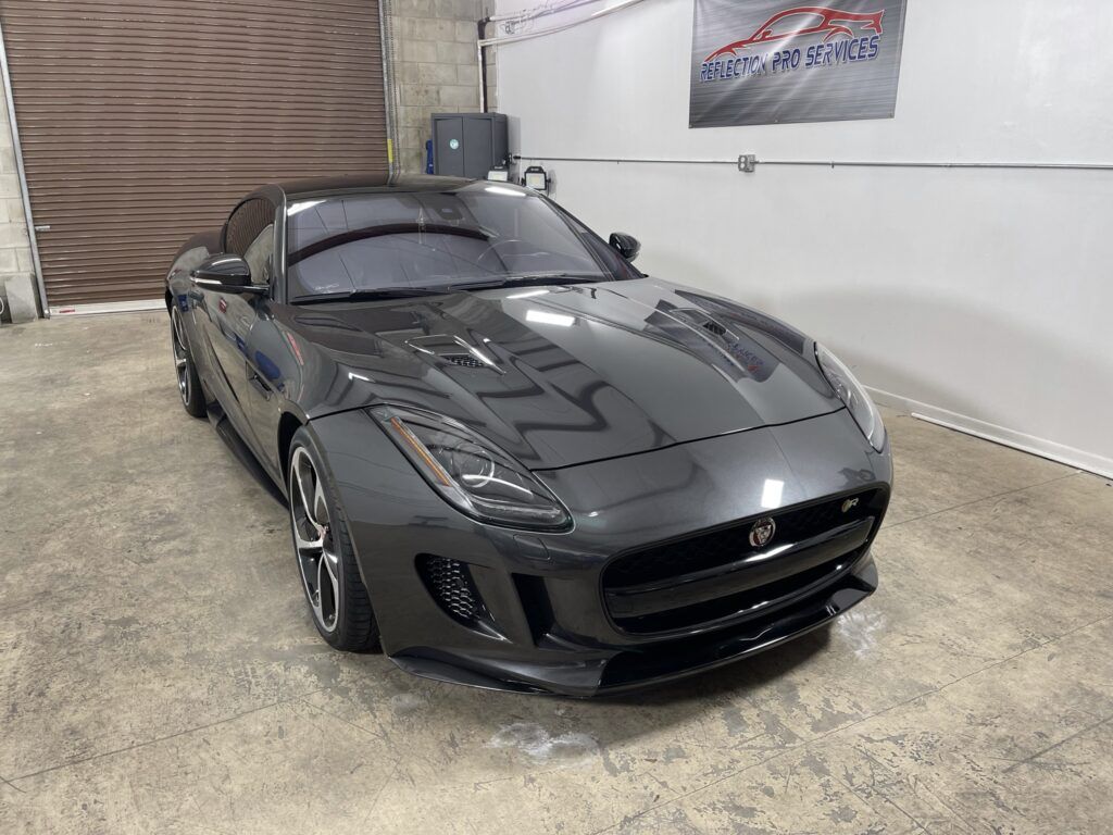 A gray jaguar f type is parked in a garage.