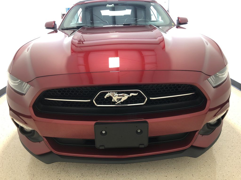 A red ford mustang is parked in a garage.