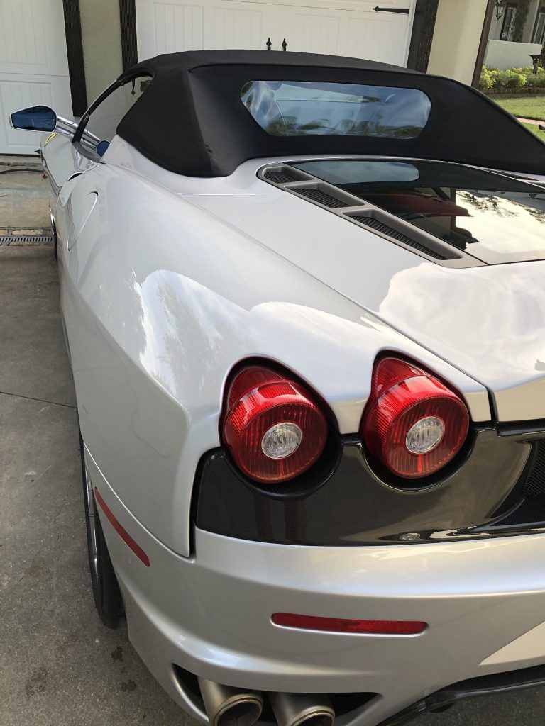 A silver sports car is parked in front of a garage door.