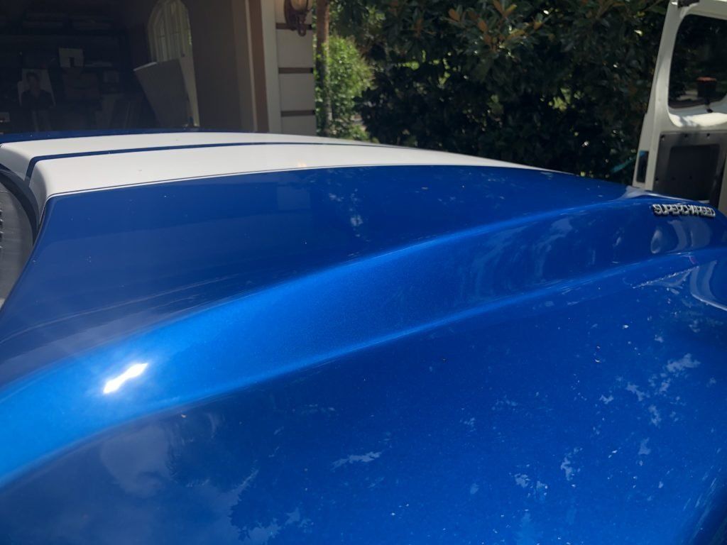 A close up of a blue and white car hood