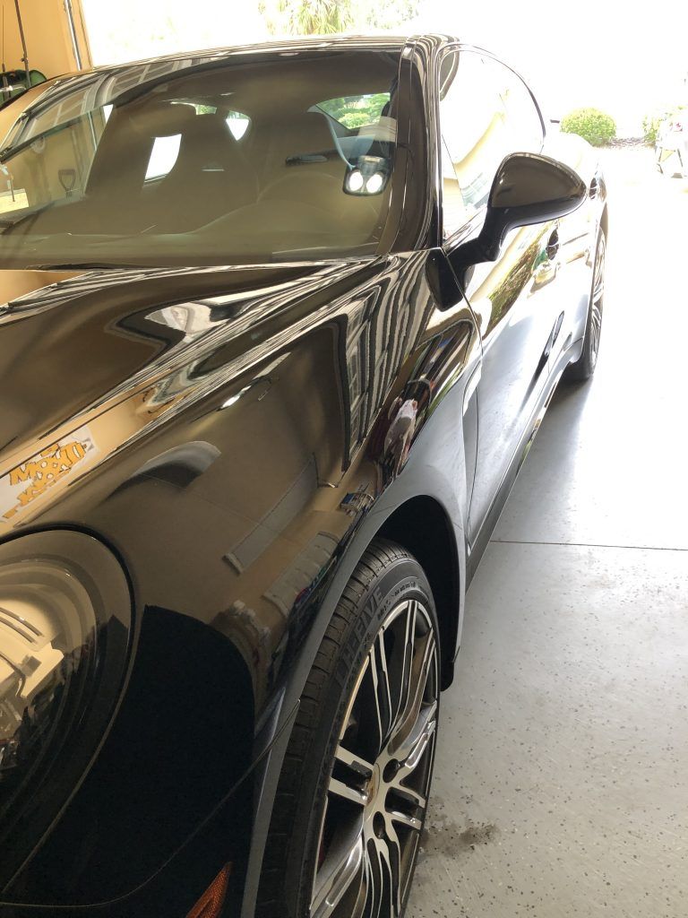 A black sports car is parked in a garage.