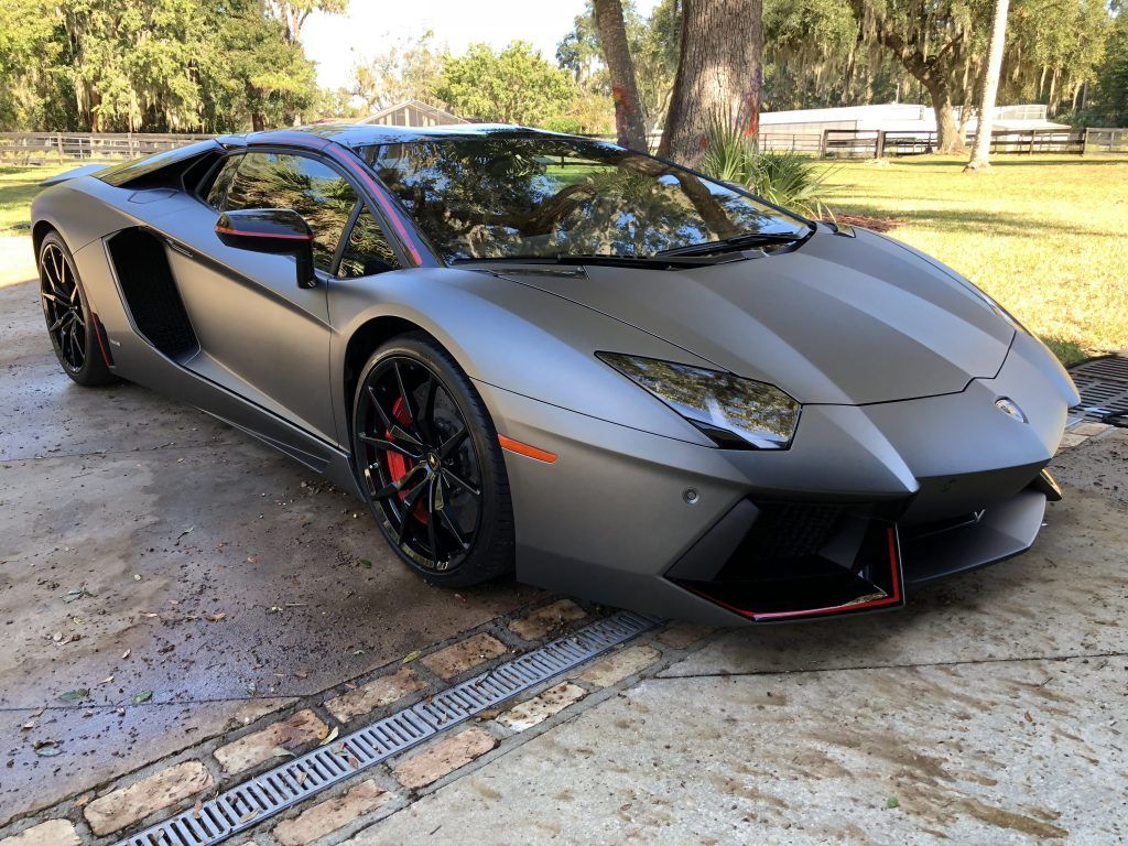 A black lamborghini aventador is parked in a driveway.