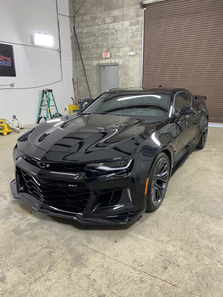 A black chevrolet camaro zl1 is parked in a garage.